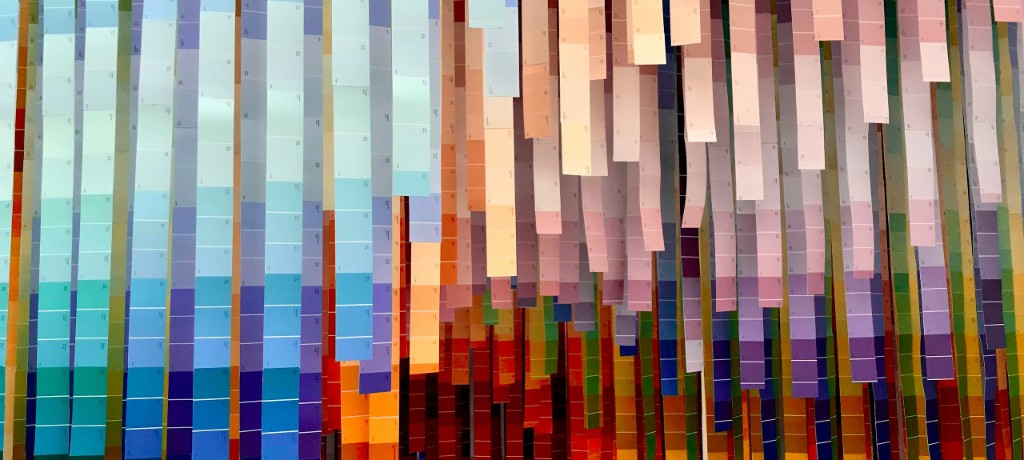 Wide panoramic view of layered vertical color swatch strips hanging like a curtain.